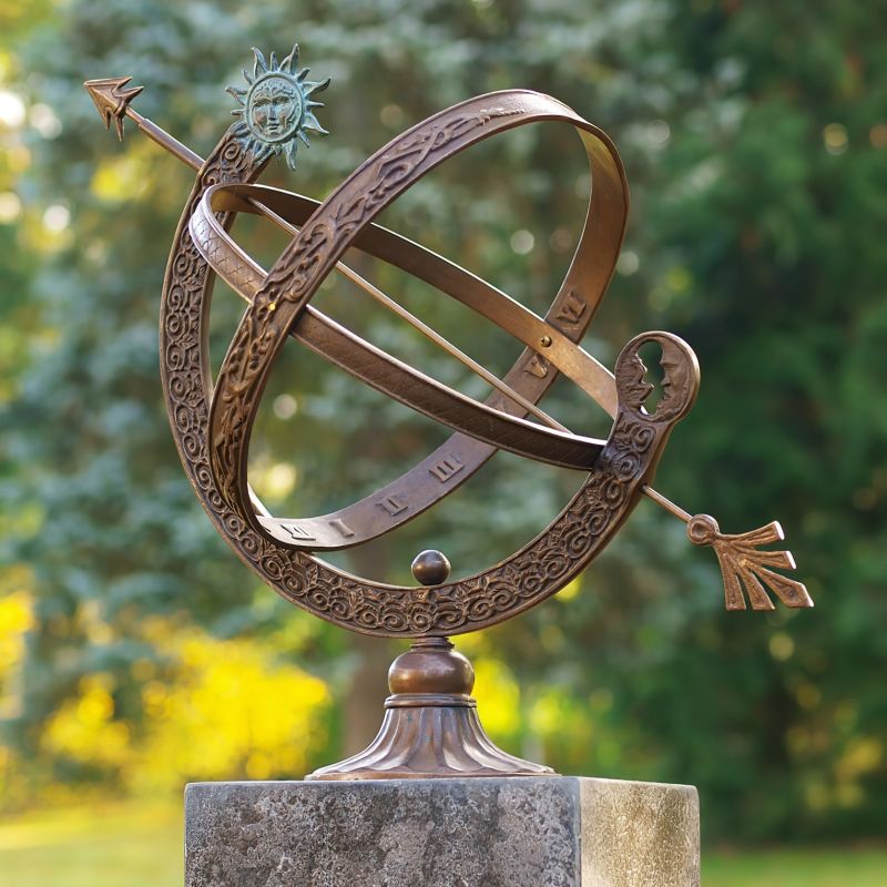 Cadran solaire en bronze orné de gravures artistiques sur un socle en pierre dans un jardin